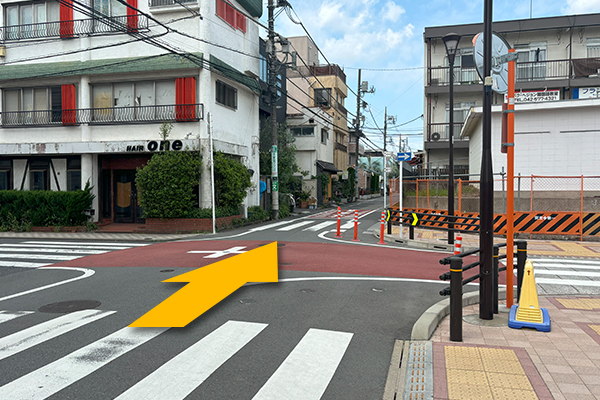 少し進むと、交差点が見えてきます。<br>交差点を渡って更に進んでください。